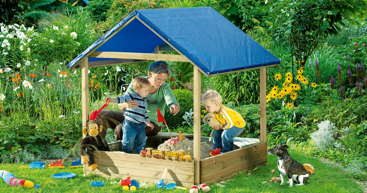 Kinder spielen in einem überdachten Sandkasten in einem Garten